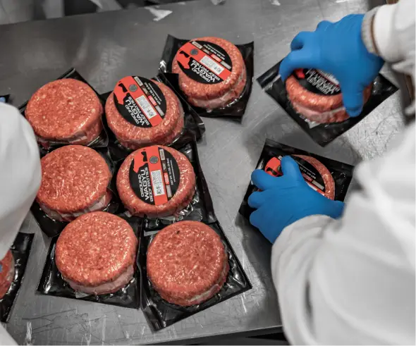 Equipo empacando hamburguesas de res porcionadas